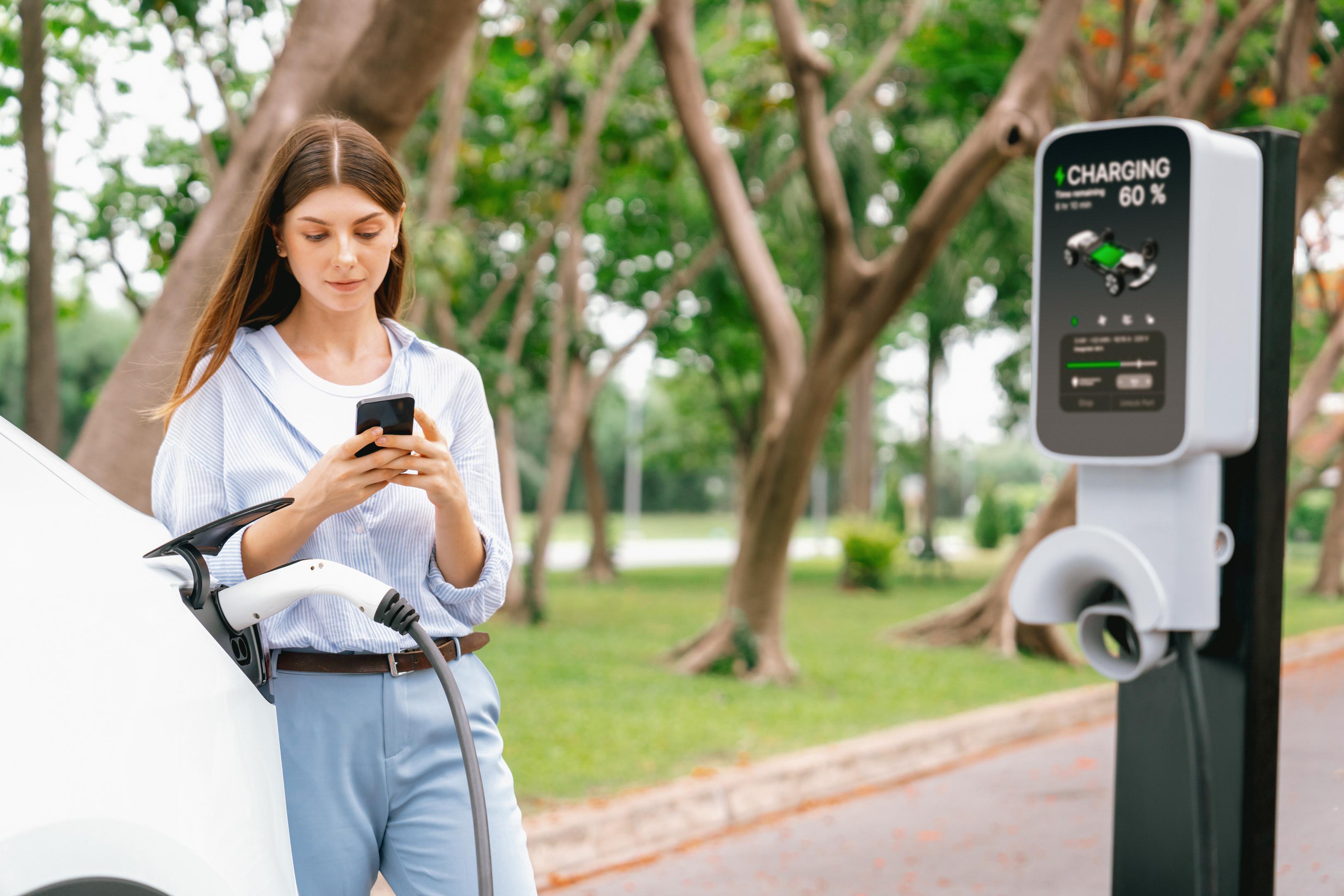 A happy person using a mobile app to interact with their electric vehicle